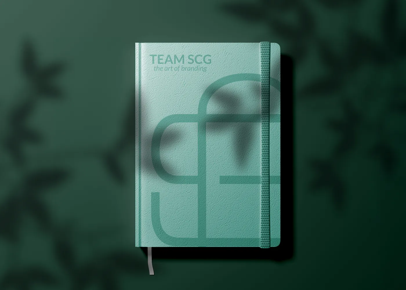A TEAM SCG branded notebook on a leafy green surface